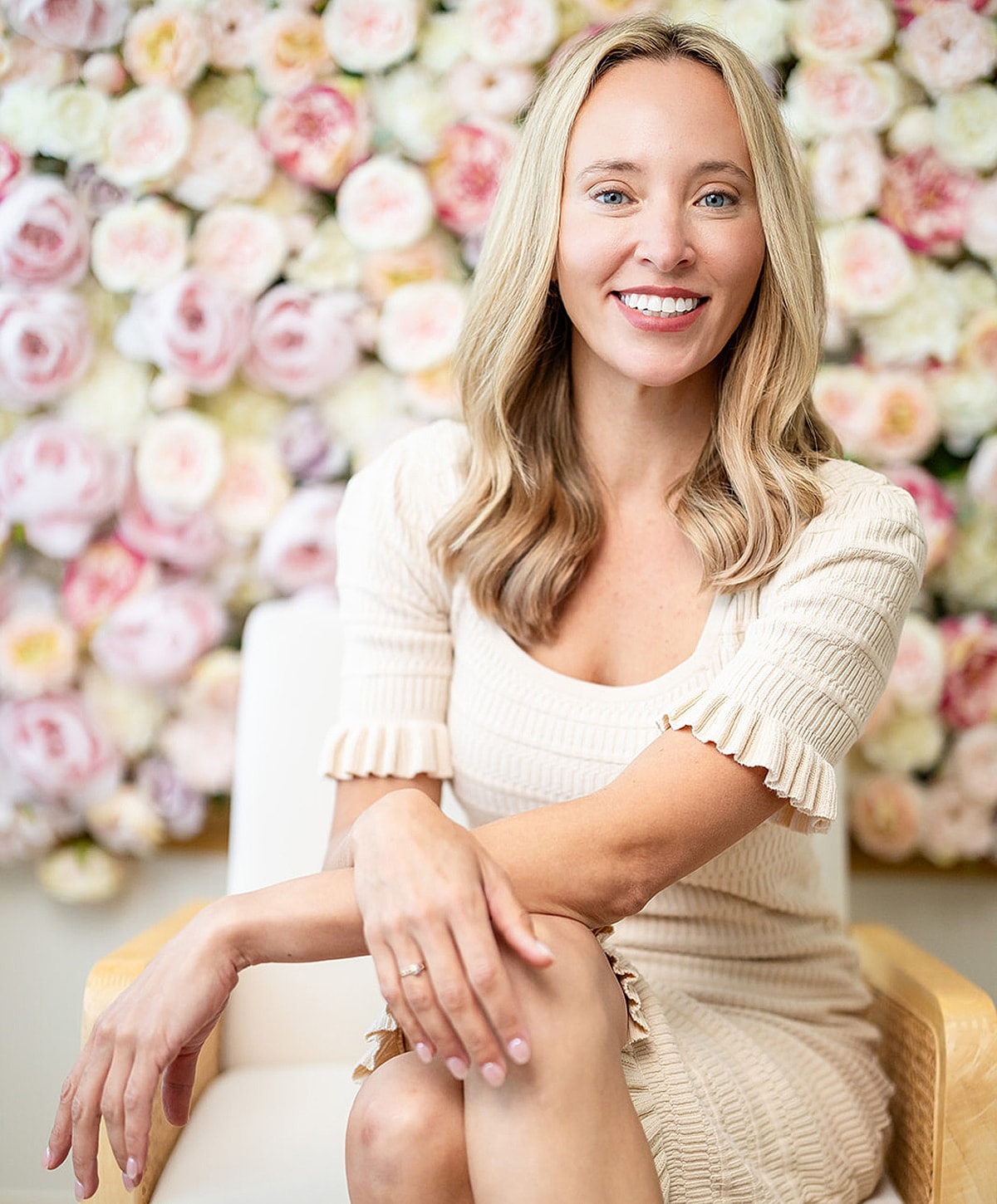 Smiling woman sitting in front of floral background.