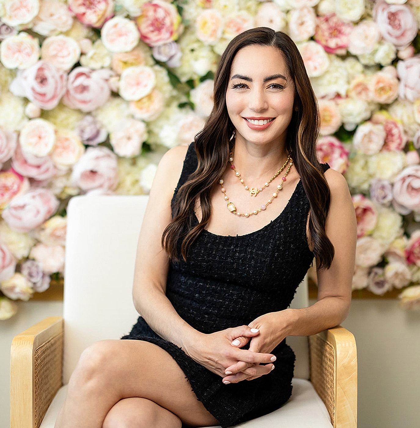 Woman in black dress against floral backdrop.