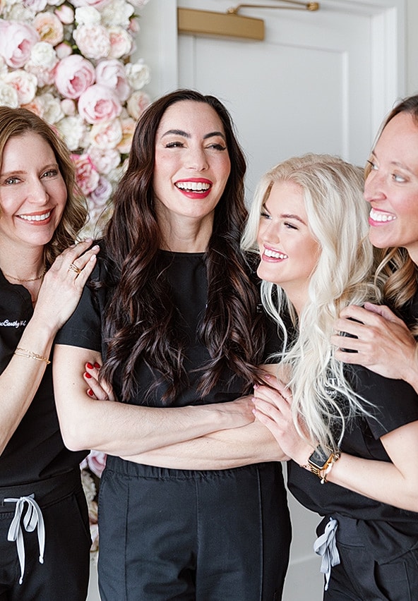 Four women smiling together in a cheerful moment.
