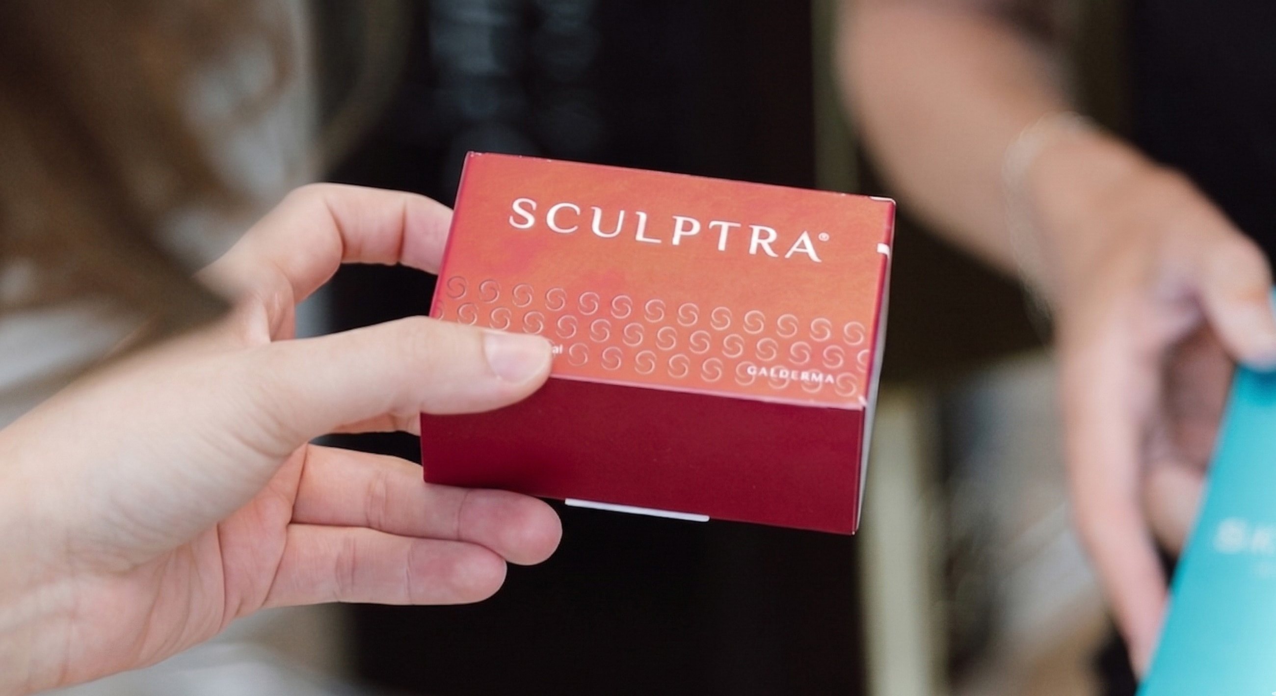 Hand holding a box of Sculptra product.